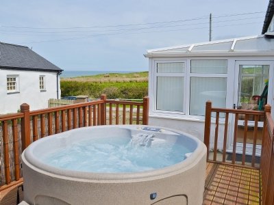Relax in the hot tub at Porth Colmon Farmhouse